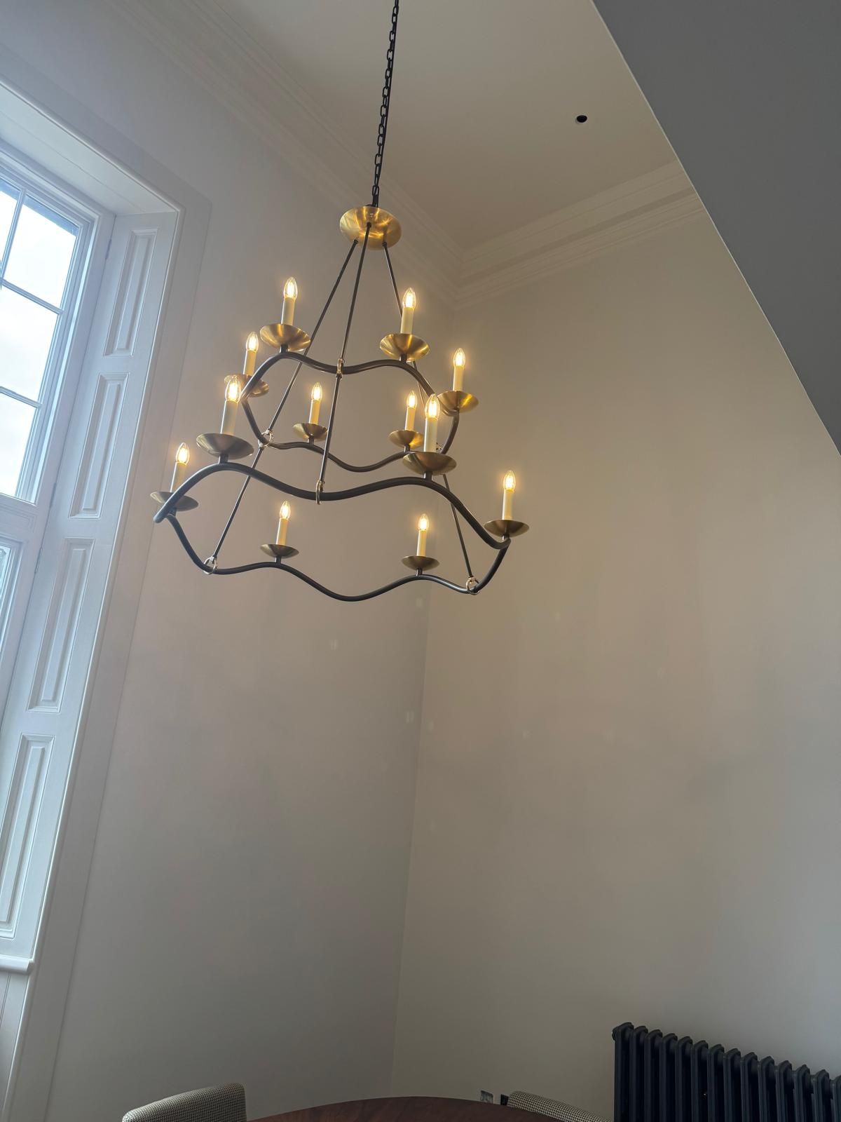 Two-tier candle chandelier hung in a tall bright room