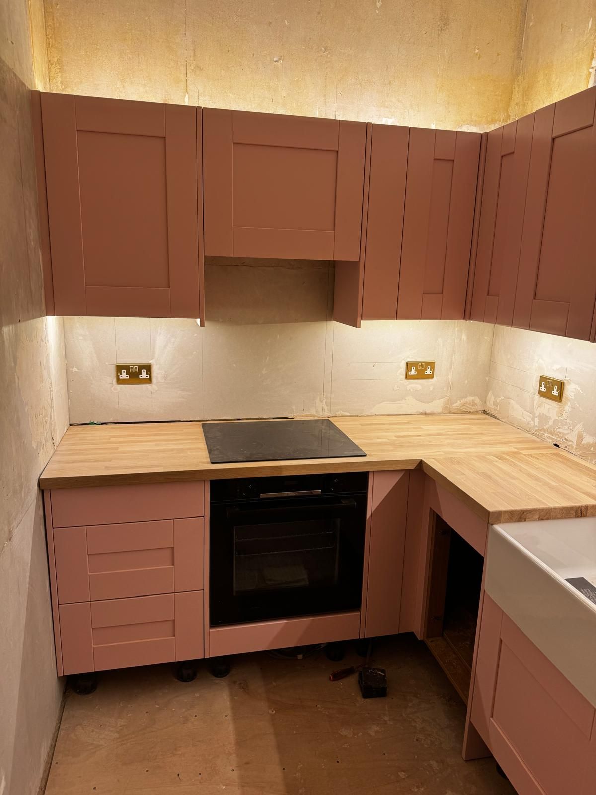 Pink shaker kitchen with under-cabinet LED lighting and new sockets